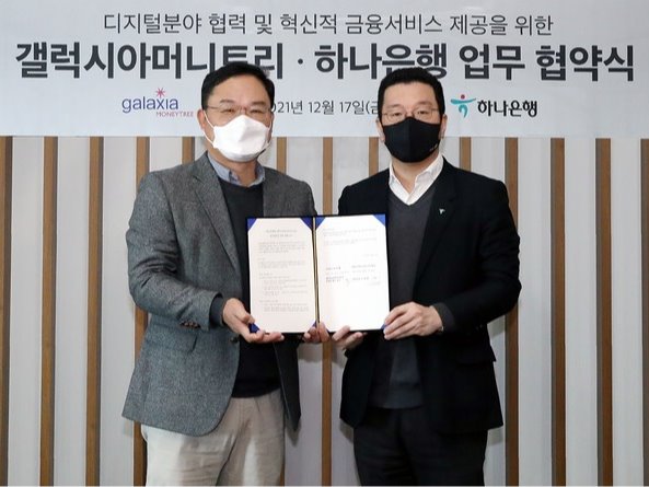 ▲ 협약식에 참석한 황보현우 하나은행 데이터&제휴투자본부장(사진 오른쪽)과 신동훈 갤럭시아머니트리 대표이사(사진 왼쪽)가 협약서를 들고 기념촬영을 하고 있다. 사진=하나은행.