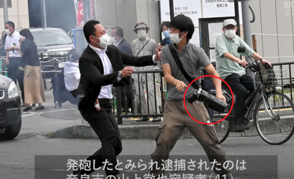 ▲ 8일 나라시에서 아베 신조 전 일본 총리를 총격한 용의자 야마가미 테츠야가 보안 요원에 의해 제지받고 있다. 용의자가 사용한 총기(적색원)는 3D프린터로 제작됐다는 의견이 나온다. 사진=아사히신문