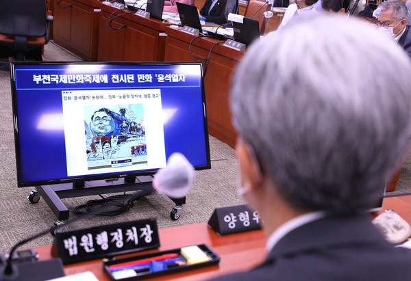 ▲ 김상환 법원행정처장이 4일 국회에서 열린 대법원 등에 대한 법제사법위원회 국정감사에 출석해 더불어민주당 박범계 의원이 제기한 표현의 자유 관련 질의 자료로 부천만화축제 전국학생만화공모전 수상작 ＜윤석열차＞를 살펴보고 있다. 공동취재사진