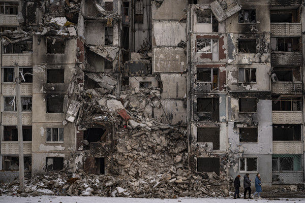▲ 지난해 2월 16일(현지시간) 우크라이나 하르키우주 살티우카 주민들이 러시아의 포격으로 파괴된 아파트 건물 앞을 지나가고 있다. 사진=뉴시스