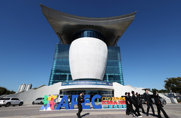 ▲ 2025 APEC CEO 서밋을 하루 앞둔 27일 오후 경북 경주시 경주예술의전당 앞에서 부스 관계자가 행사 로고 앞을 지나고 있다. 사진=뉴시스